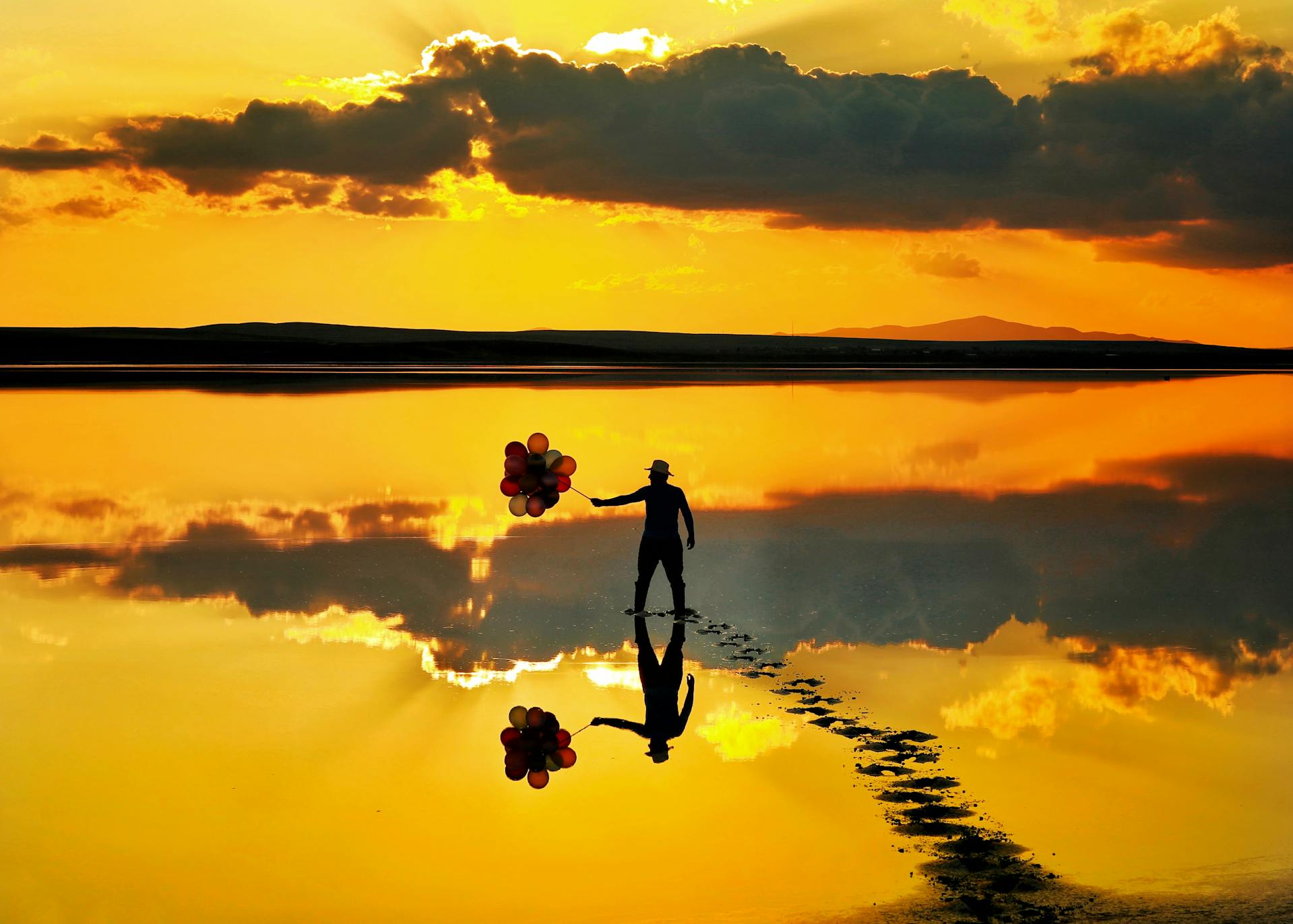 Person holding balloons on sunset beach, symbolising spiritual approaches to therapy
