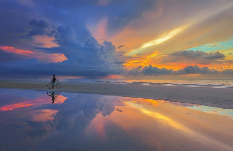 Person with bike under vanilla sky on beach, representing Spiritually Integrated Therapy supporting spiritual crisis recovery