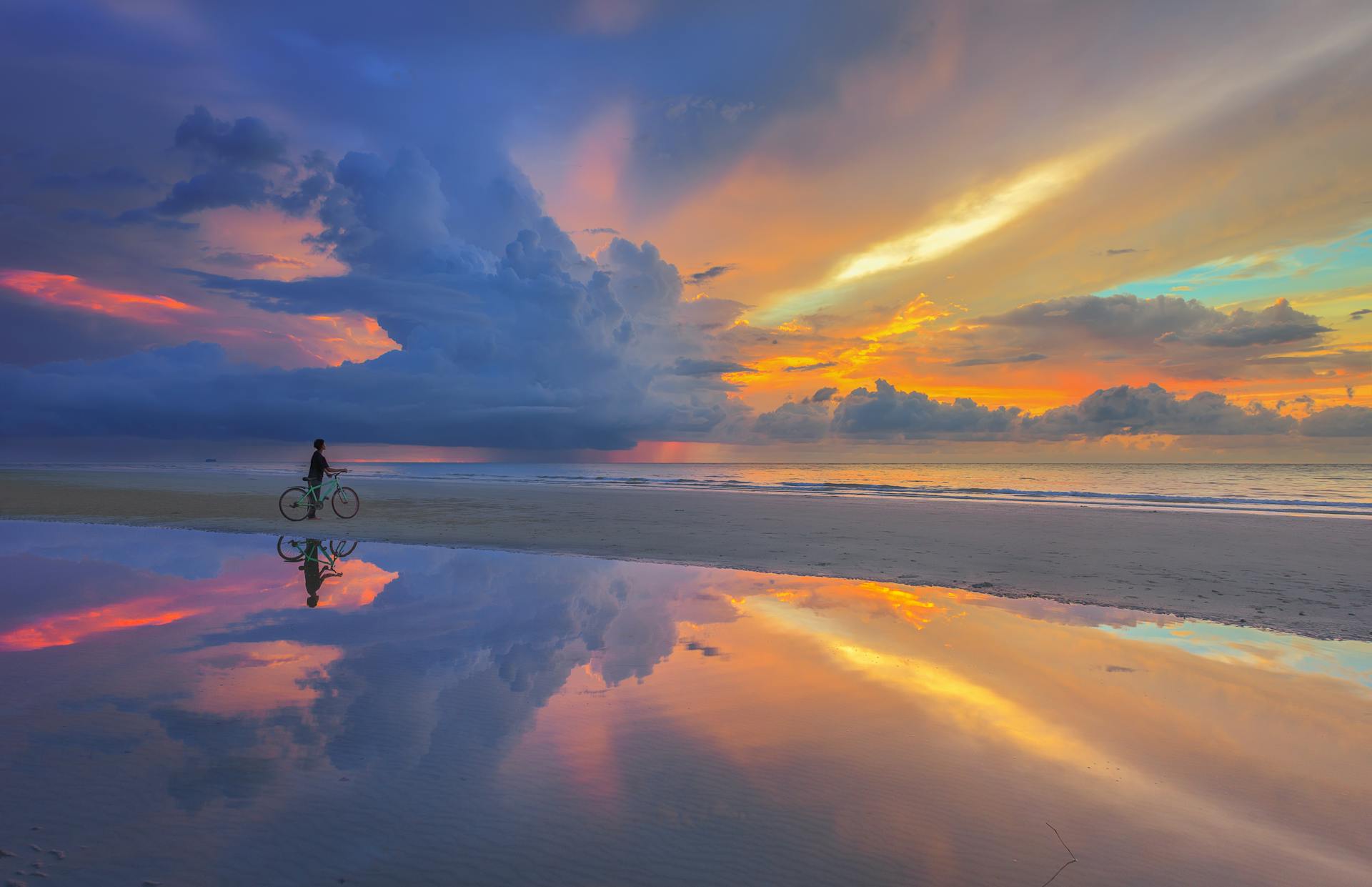 Person with bike under vanilla sky on beach, representing Spiritually Integrated Therapy supporting spiritual crisis recovery