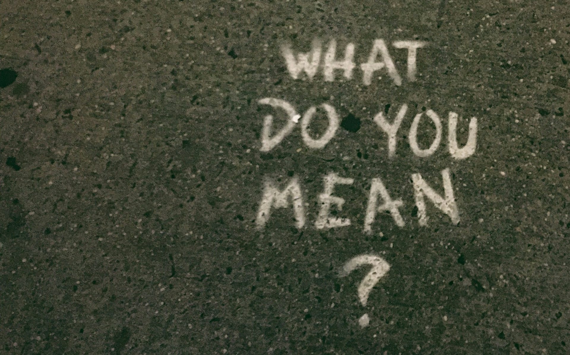 "what do you mean" spray-painted on the road, signifying a questioning of identity and life meaning