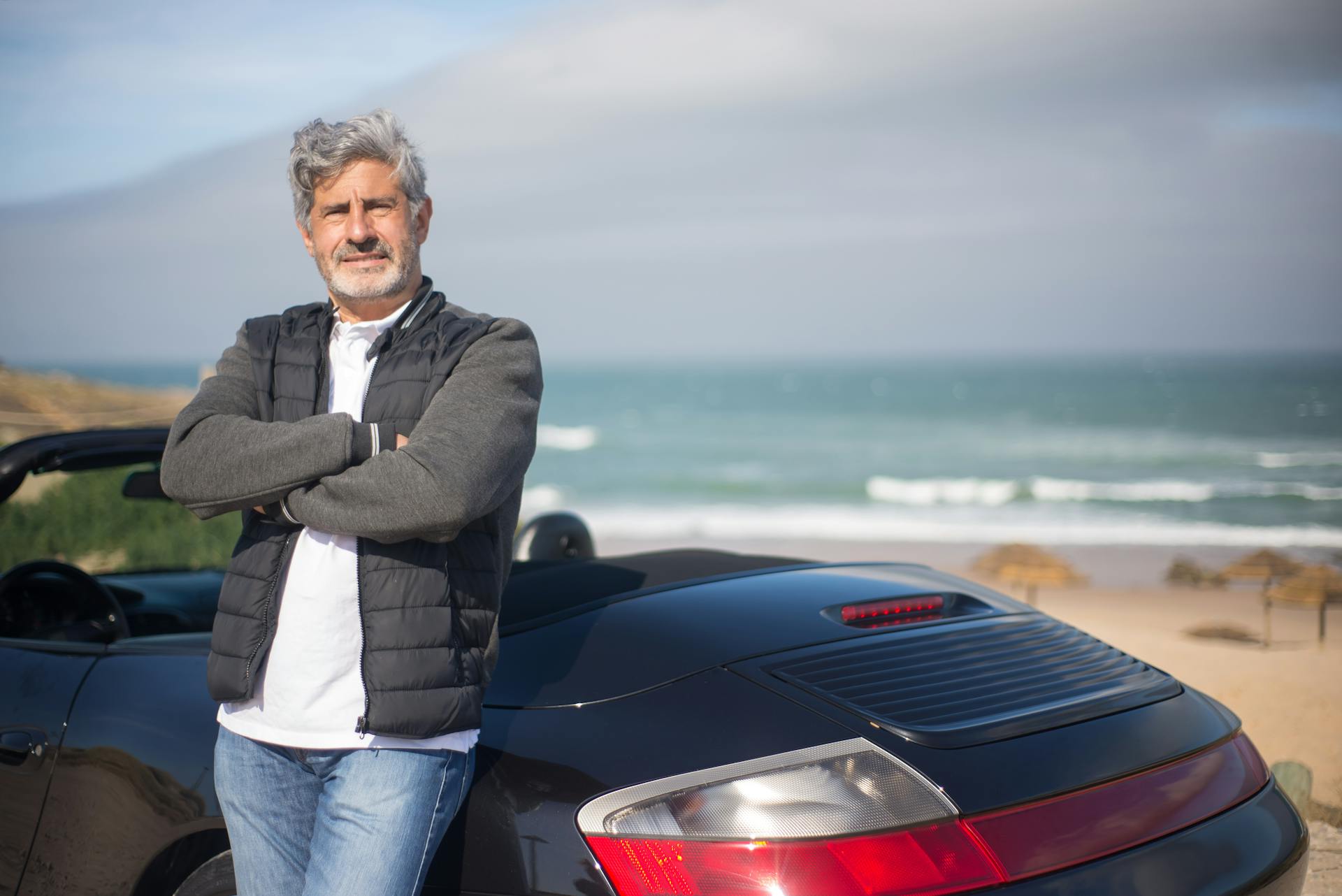 man in front of sports car, symbolising existential autonomy and intrinsic, as well as extrinsic motivation